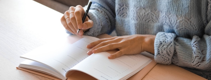 Adult writing in a planner in soft daylight, illustrating the structure and routine that support recovery for adults with ADHD