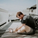 Adult doing a seated forward stretch on a sunlit deck, illustrating non-opioid approaches to chronic pain in residential care