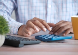 Hands using a calculator at a desk while working out the cost of luxury rehab in California
