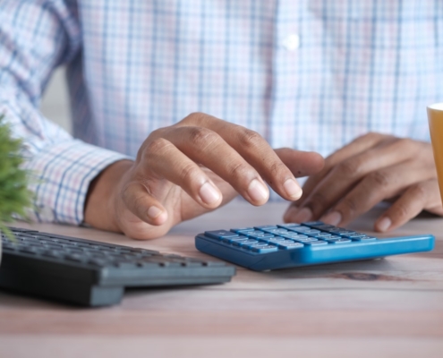Hands using a calculator at a desk while working out the cost of luxury rehab in California
