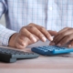 Hands using a calculator at a desk while working out the cost of luxury rehab in California