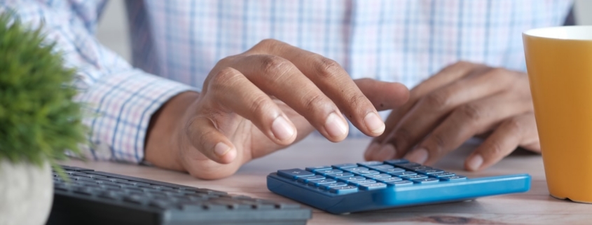 Hands using a calculator at a desk while working out the cost of luxury rehab in California