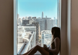 A person looking out of a window in reflective light