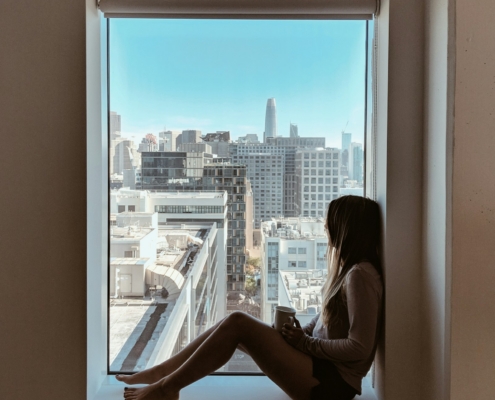 A person looking out of a window in reflective light