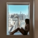 A person looking out of a window in reflective light