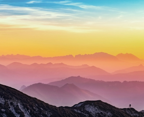 Person standing on a mountain ridge watching the sunrise, symbolizing hope and a fresh start in addiction recovery