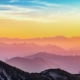 Person standing on a mountain ridge watching the sunrise, symbolizing hope and a fresh start in addiction recovery