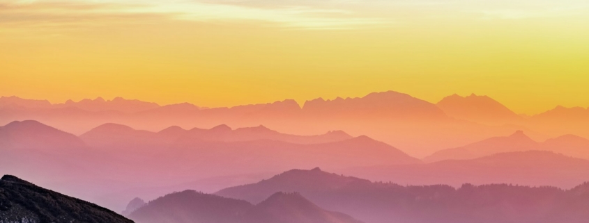 Person standing on a mountain ridge watching the sunrise, symbolizing hope and a fresh start in addiction recovery
